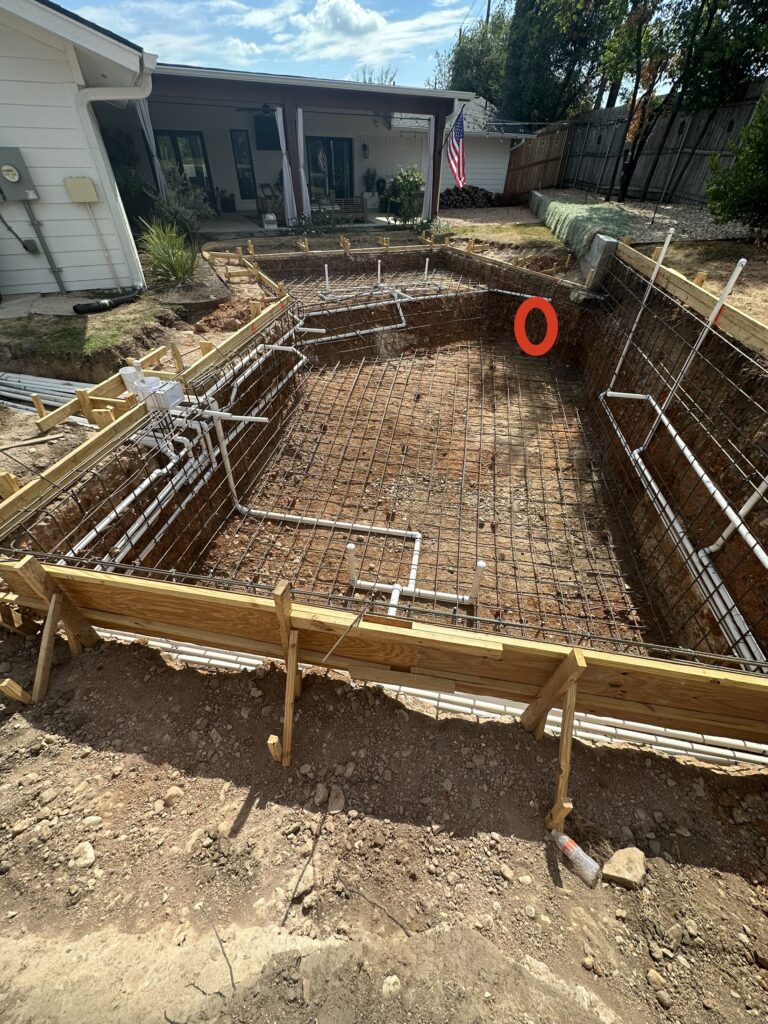 Gunite pool under construction with rebar and plumbing in Austin, TX