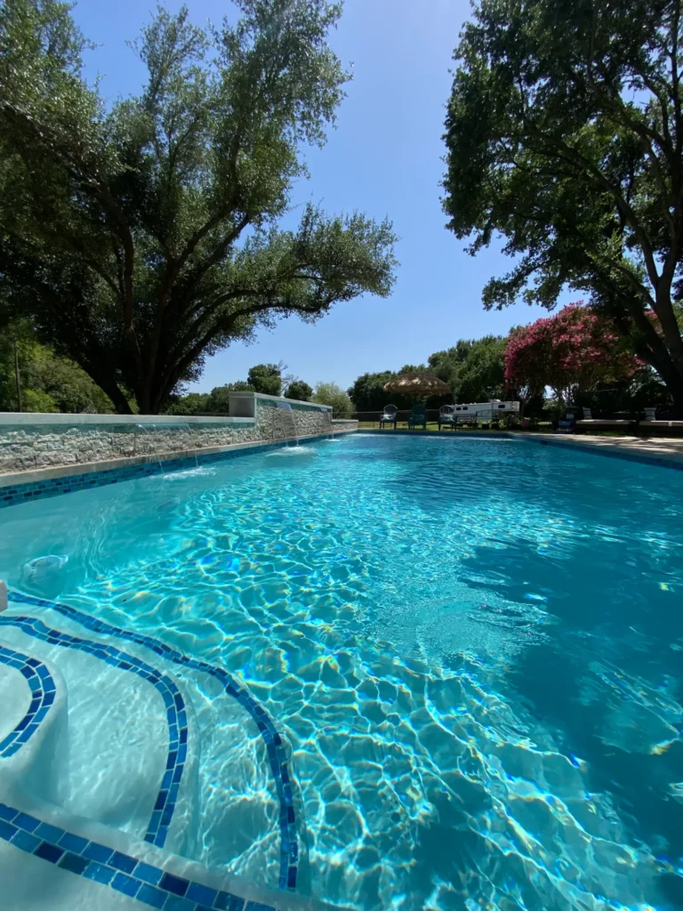 Long rectangular pool with stone coping and raised wall in Austin