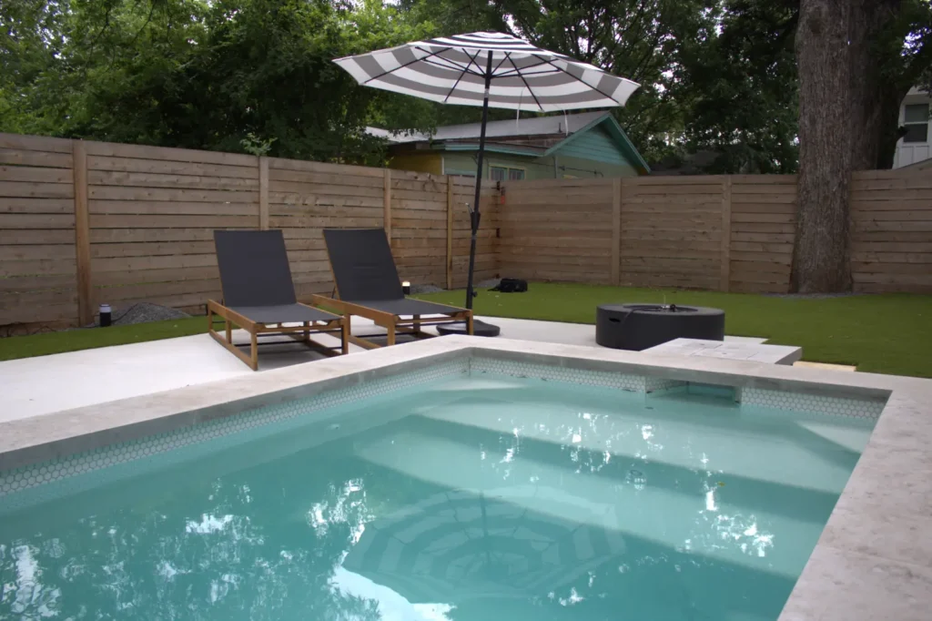 Rectangular pool with tanning ledge and loungers in an Austin backyard